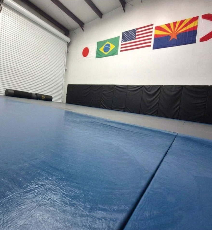 Empty training mats and flags inside the Infinite BJJ and MMA gym